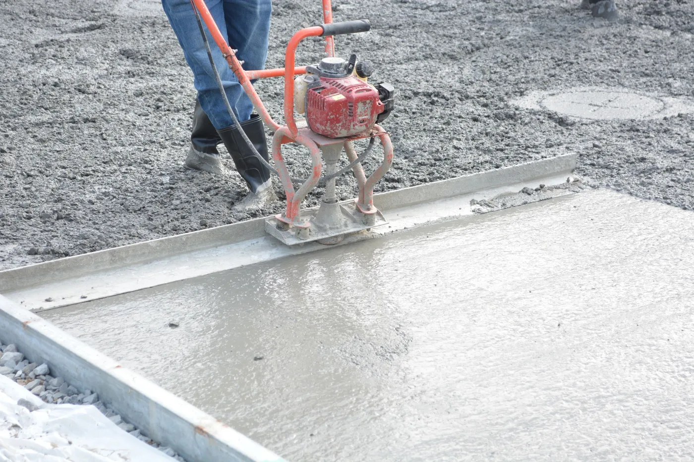 A power trowel finishing a freshly poured concrete house slab.